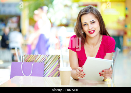 Lächelndes Mädchen mit einem digitalen Schreibblock am Tisch in einem Sommercafé Stockfoto