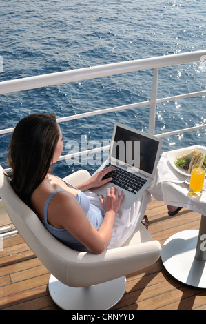 schöne junge Frau, die Arbeiten auf dem Kreuzfahrtschiff mit Laptop-computer Stockfoto