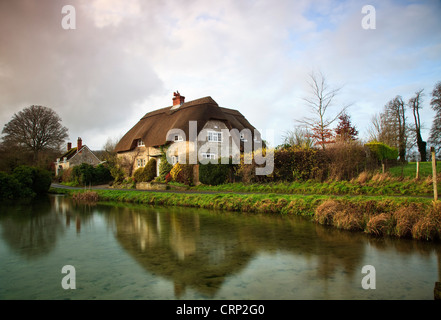 Blick über einen Teich in Richtung strohgedeckten Hütten am Sherrington. Stockfoto