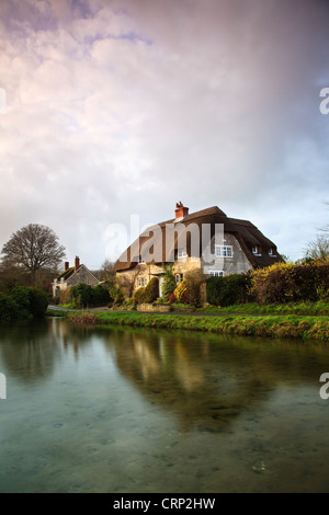 Blick über einen Teich in Richtung strohgedeckten Hütten am Sherrington. Stockfoto