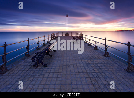 Sonnenaufgang über dem Banjo geformt Badesteg in Swanage Bay. Stockfoto