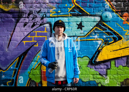 Graffiti-Künstler halten eine Spray kann vor ein großes Stück der Straßenkunst. Stockfoto