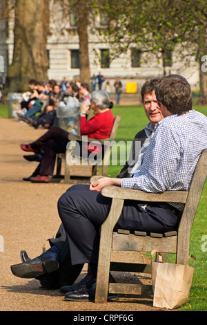 Büroangestellte entspannend auf den Bänken im St James Park zur Mittagszeit. Stockfoto