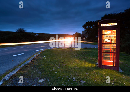 Lichtspur aus einem Auto vorbei eine rote Telefonzelle an der Seite einer Straße im Dartmoor National Park. Stockfoto