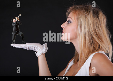Mann Trompete spielen für schöne blonde Frau in weißen Handschuhen schwarzen Hintergrund Stockfoto