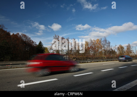Geschwindigkeitsüberschreitung-Konzept - Autos bewegen schnell auf der Autobahn an einem schönen Herbst/Herbst-Tag (die Autos sind Bewegung verwischt, um Bewegung zu vermitteln) Stockfoto