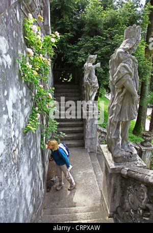 Eine Frau riechen ein Klettern stieg Busch in den Gärten der Villa Cipressi Varenna See Como Italien italienischen Region Lombardei Stockfoto