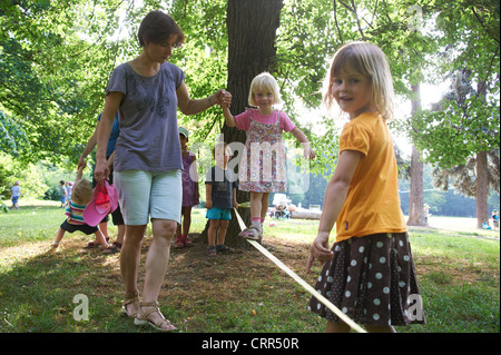 Kinder und Eltern Slacklinen im Sommerpark Stockfoto