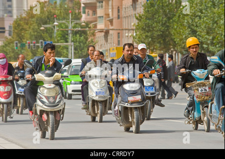 Eine komprimierte perspektivische Ansicht des Menschen auf Roller unterwegs an einer Hauptstraße in Kashgar. Stockfoto