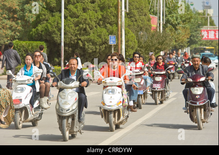 Eine komprimierte perspektivische Ansicht des Menschen auf Roller unterwegs an einer Hauptstraße in Kashgar. Stockfoto