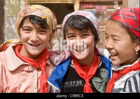 3 lächelnde junge uigurische chinesische Mädchen posieren für die Kamera auf der Straße in der alten Stadt Kashgar. Stockfoto