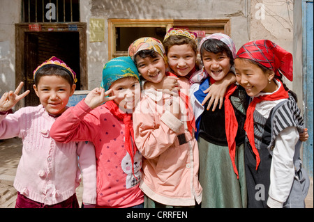 Eine Gruppe von lächelnden jungen Uyghur chinesische Kinder posieren für die Kamera auf der Straße in der alten Stadt Kashgar. Stockfoto