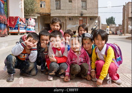 Eine Gruppe von lächelnden jungen Uyghur chinesische Kinder posieren für die Kamera auf der Straße in der alten Stadt Kashgar. Stockfoto