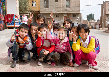 Eine Gruppe von lächelnden jungen Uyghur chinesische Kinder posieren für die Kamera auf der Straße in der alten Stadt Kashgar. Stockfoto