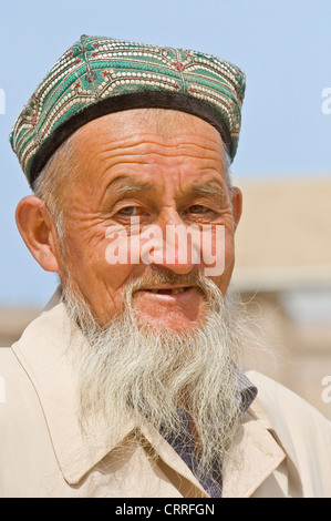 Ein Lächeln auf den Lippen Eldely Uyghur Chinesisch Mann posiert für die Kamera auf der Straße in Kashgar die traditionellen Dopa Hut. Stockfoto