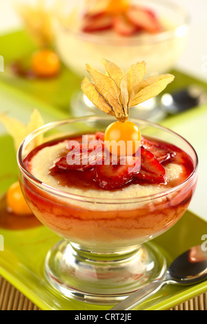 Grieß-Pudding mit Erdbeeren, Erdbeersauce und eine Physalis in eine Glasschüssel Stockfoto