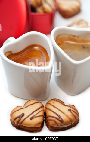 herzförmige Creme Cookies auf rotes Herz Metallbox und paar Espresso Kaffeetassen Stockfoto