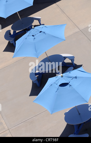Abstraktes Bild von blauen Sonnenschirmen und schattigen Tischen Stockfoto