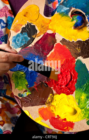 Frau mit bunten Farben und Lack Pinsel beim Mischen der Farbe Stockfoto