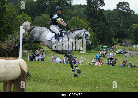 Weibliche Veranstaltung Reiter und Pferd, die Landung nach dem Sprung Pinsel Zaun aus Wasser-Komplex an Glanusk International Horse Trials Stockfoto