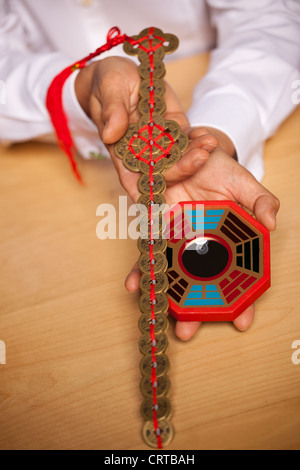 Hände des Mannes hält chinesischen Feng Shui Spiegel und Schwert Stockfoto