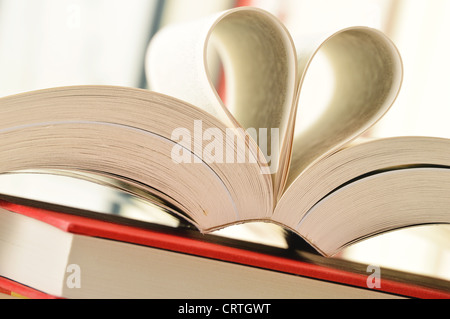 Komposition mit Stapel von Büchern und Seiten gebildet in Form von Herzen Stockfoto