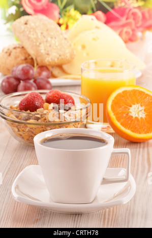 Frühstück auf dem Tisch. Kaffee, Orangensaft, Brötchen, Müsli. Stockfoto