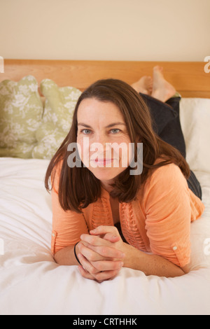 Frau liegend auf dem Bett lächelnd und in die Kamera schaut. Stockfoto