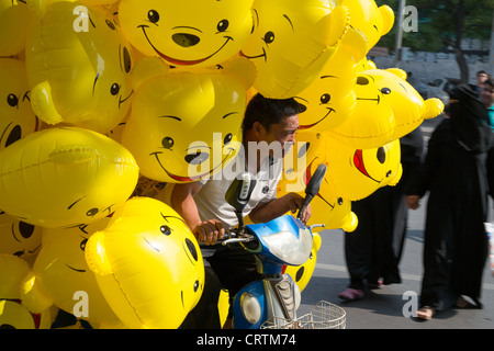 Mann mit Winnie The Pooh Luftballons in die gehobene Einkaufsviertel der Sanlitun in Beijing, China. Stockfoto