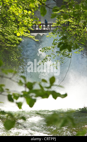 Menschen sind eine Holzbrücke über einen mächtigen Wasserfall ausgesetzt Fuß. Stockfoto