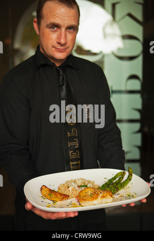 Mann mit sautierten Wolfsbarsch mit Spargel, Petros Greek Restaurant, Santa Barbara, Kalifornien Stockfoto