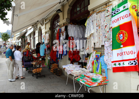 Touristen, Einkaufen, Handtücher für den Strand und Kunsthandwerk hängen außerhalb Souvenir-Shop, Viana do Castelo, Nordportugal Stockfoto