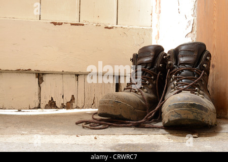 Schlammigen Wanderstiefel Stock neben eine alte verwitterte Tür Stockfoto