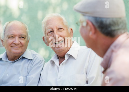 Aktiven Ruhestand, Gruppe von drei alten männlichen Freunden reden und Lachen auf Bank im öffentlichen park Stockfoto