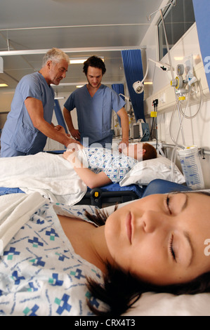 Ein Chirurg (links) und ein Mitglied von seinem chirurgischen Team sprechen mit den Patienten während der Visite im Krankenhaus. Stockfoto