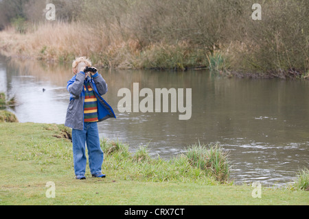 Junge mit dem Fernglas in die Landschaft von einem Fluss Stockfoto