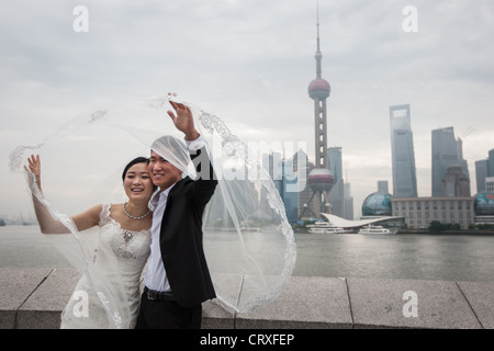 Junge chinesische Paare haben Hochzeitsfotos geschossen, am frühen Morgen auf den Bund mit Pudong in Shanghai, China Hintergrund Stockfoto