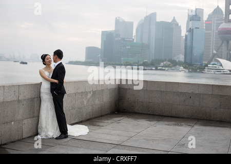 Junge chinesische Paare haben Hochzeitsfotos geschossen, am frühen Morgen auf den Bund mit Pudong in Shanghai, China Hintergrund Stockfoto