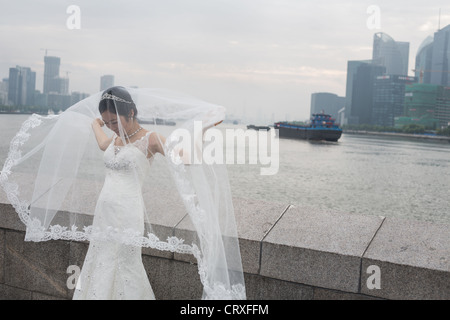 Junge chinesische Paare haben Hochzeitsfotos geschossen, am frühen Morgen auf den Bund mit Pudong in Shanghai, China Hintergrund Stockfoto