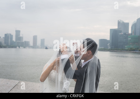 Junge chinesische Paare haben Hochzeitsfotos geschossen, am frühen Morgen auf den Bund mit Pudong in Shanghai, China Hintergrund Stockfoto
