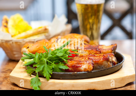 Gegrillte Schweinerippchen und Gemüse hautnah. Mit Brot und Bier im restaurant Stockfoto