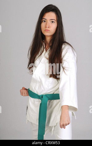 Mädchen im Karate bewegt sich auf grauem Hintergrund Stockfoto