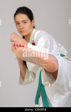 Mädchen im Karate bewegt sich auf grauem Hintergrund Stockfoto