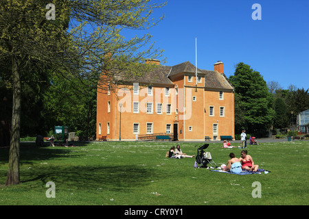 Menschen sitzen auf dem Rasen entspannend vor Pittencrieff Haus Museum im Pittencrieff Park in Dunfermline, Fife, Schottland Stockfoto