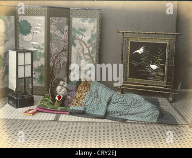 Koloriertes Foto von zwei Frauen, die auf einem Futon schlafen und mit einer Decke bedeckt sind, mit ihren Köpfen auf hölzernen Kopfstützen, Japan, um 1880. (Foto von Kusakabe Kimbei) Stockfoto
