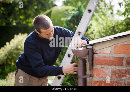 Workman behebt Dachrinnen auf Dach Stockfoto