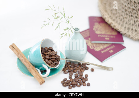 Eine helle Tischplatte Szene mit hellen blauen Kaffeetassen mit Kaffeebohnen und Zimt-stick eine Vase mit zwei britischen Pas Wildgras Stockfoto