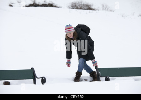 Junge Frau, die Vermeidung von Tiefschnee, Parkbank im verschneiten Tromsø, Norwegen zu erreichen Stockfoto