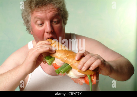 Fetter Mann im Unterhemd Essen eine große baguette Stockfoto