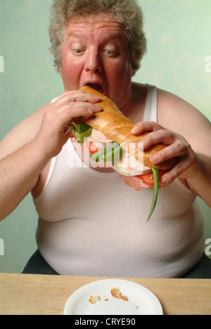 Fetter Mann im Unterhemd Essen eine große baguette Stockfoto